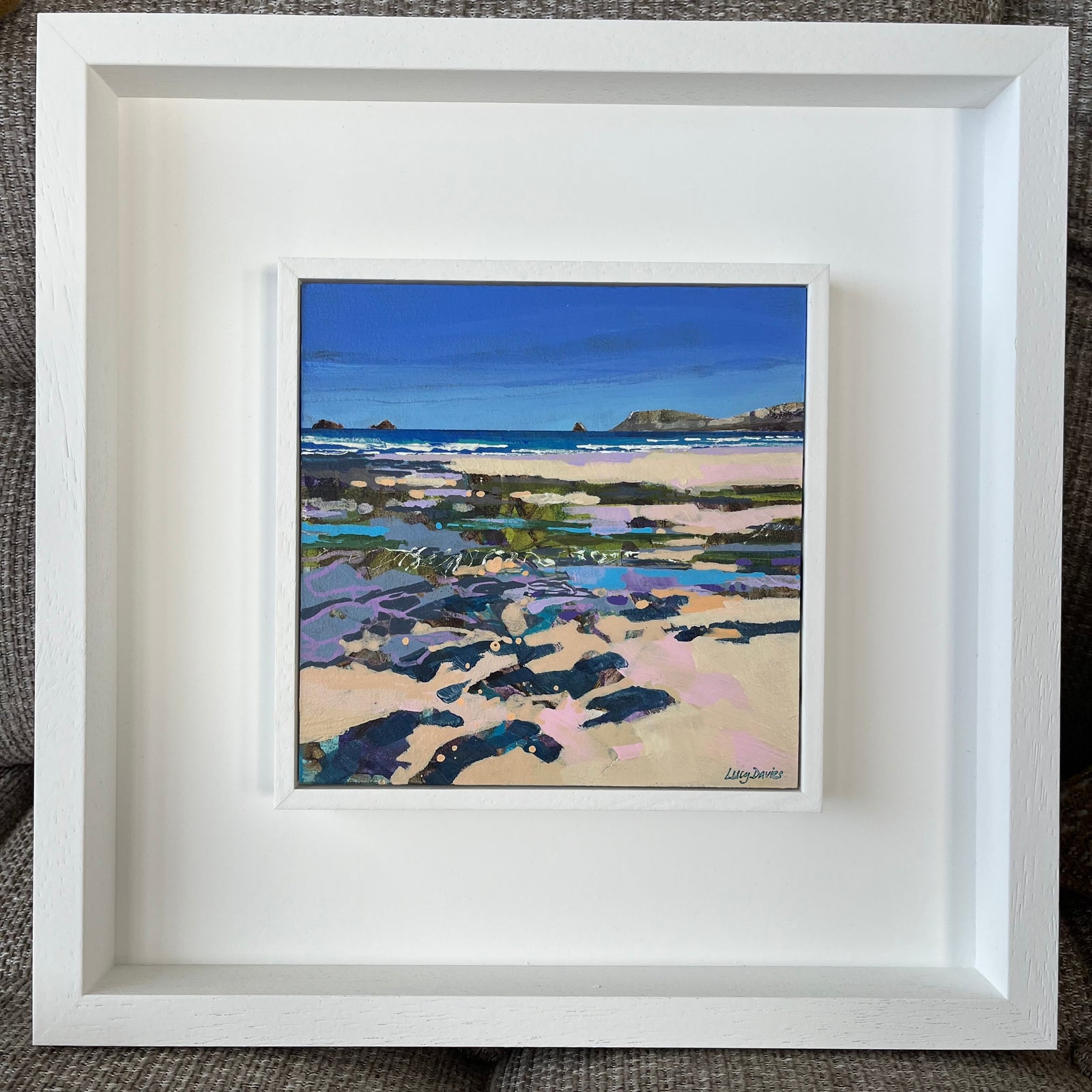 Framed artwork of a coastal landscape with a white frame.