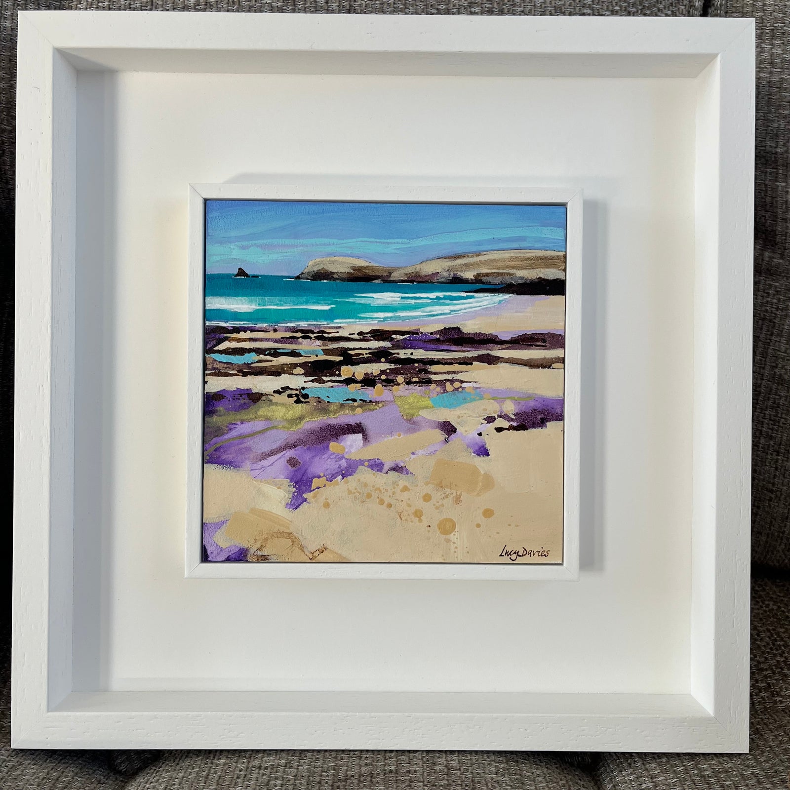 Framed artwork of a beach scene with a white frame